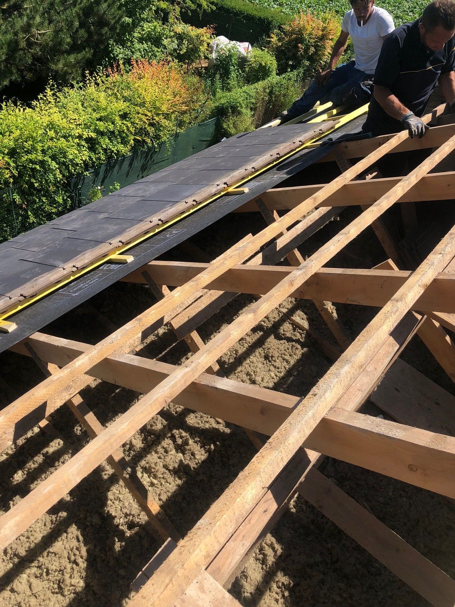 Un homme mesure le toit d'un bâtiment avec un ruban à mesurer.