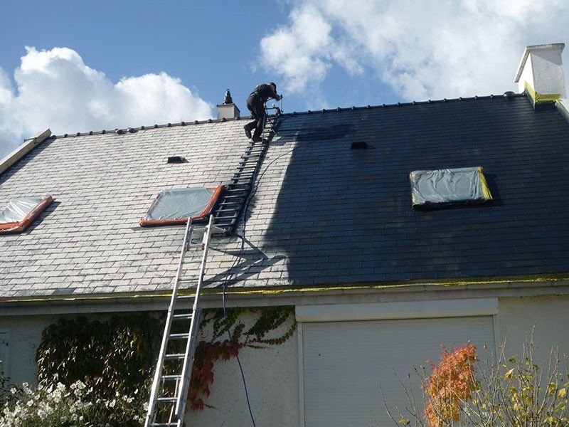 Un homme est debout sur une échelle sur le toit d'une maison.